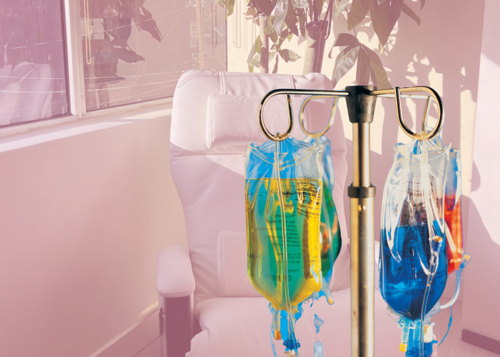 IV vitamin infusion bags filled with colorful fluids hanging in a bright, modern wellness lounge chair setup.