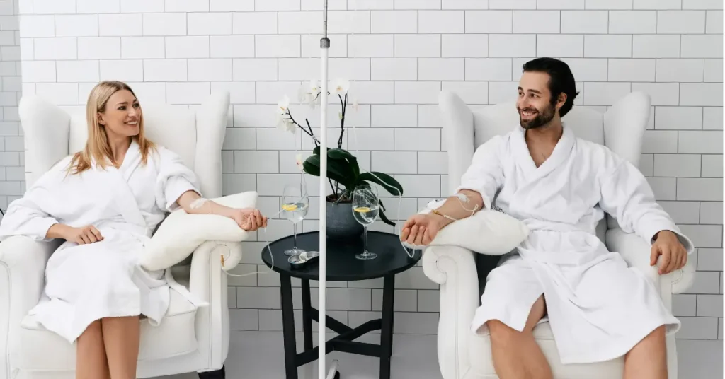 IV vitamin drip therapy being enjoyed by a relaxed couple in white robes at a modern wellness clinic