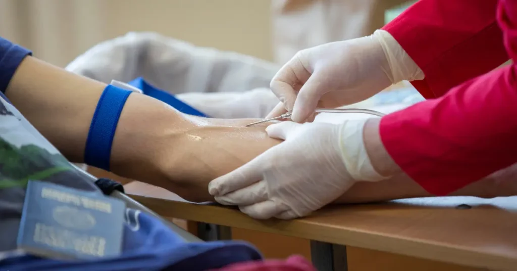 Ketamine assisted therapy procedure showing close-up of IV needle insertion into patient’s arm by gloved clinician.