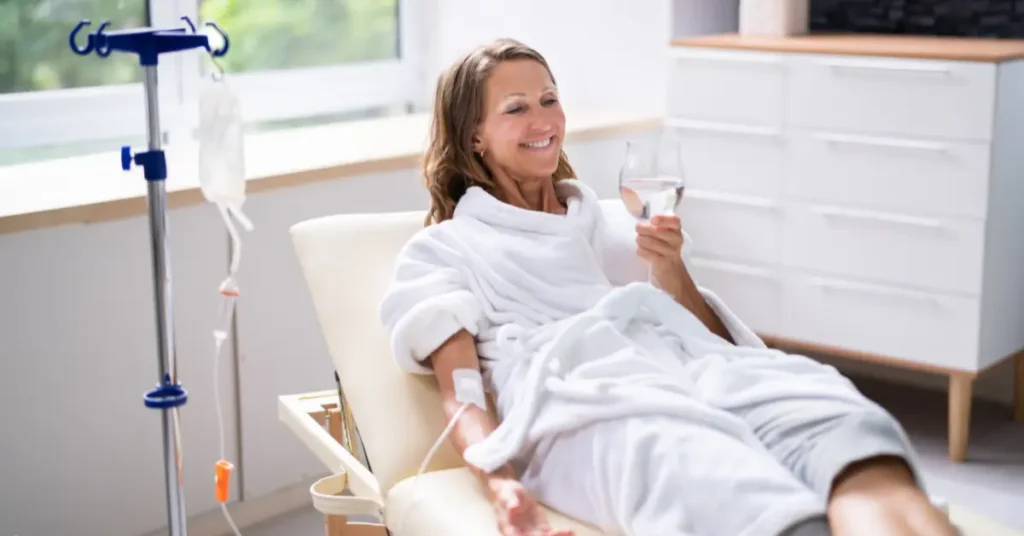 Ketamine infusion therapy session with smiling woman relaxing in chair and receiving IV drip.