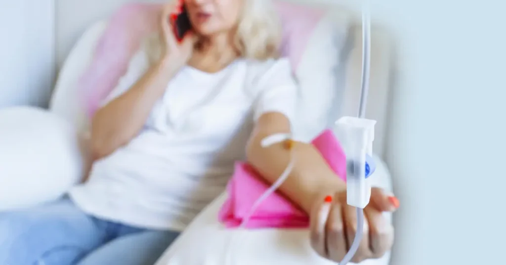 Mental wellness treatment with woman receiving IV therapy while speaking on phone in a comfortable setting