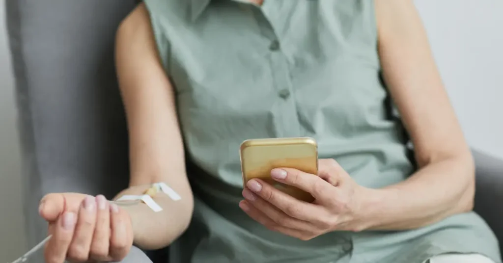 IV vitamin infusion session with a woman checking her phone while receiving treatment in a casual chair.