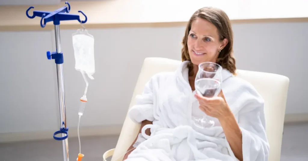 Depression treatment alternatives shown with relaxed woman receiving IV therapy and holding a glass of water.