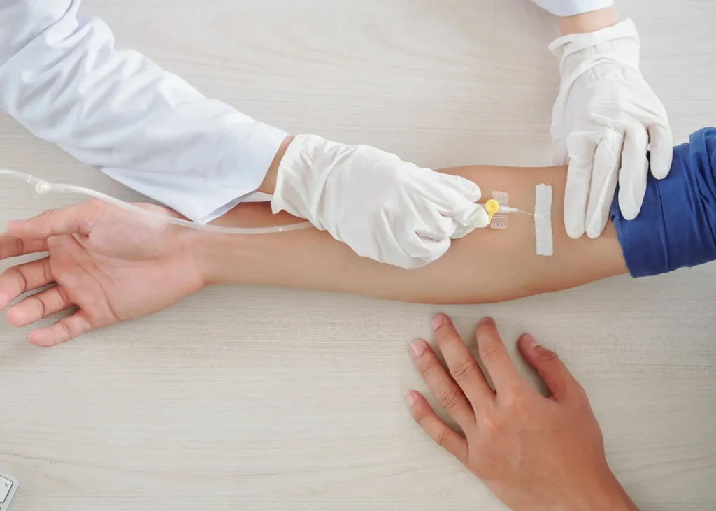 IV nutrient therapy being administered through a catheter into a patient's forearm by a gloved medical professional