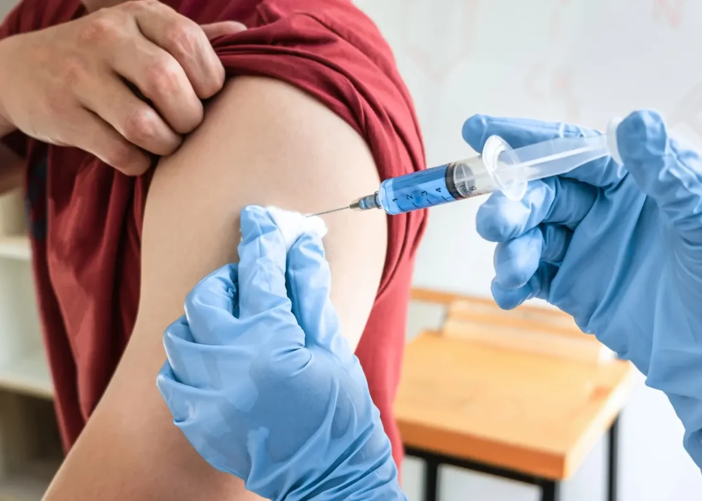 Intravenous vitamins delivered via syringe into a man’s arm by a medical worker wearing blue gloves