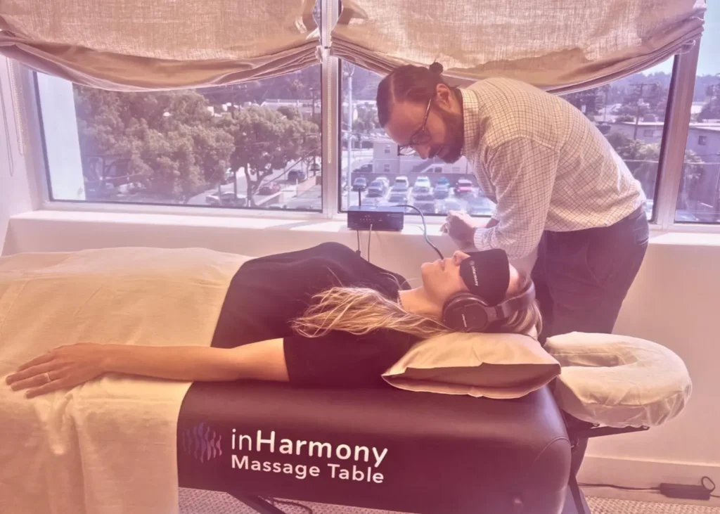 Sound therapy for stress showing a woman on a soundbed with headphones and an eye mask in a calm room.