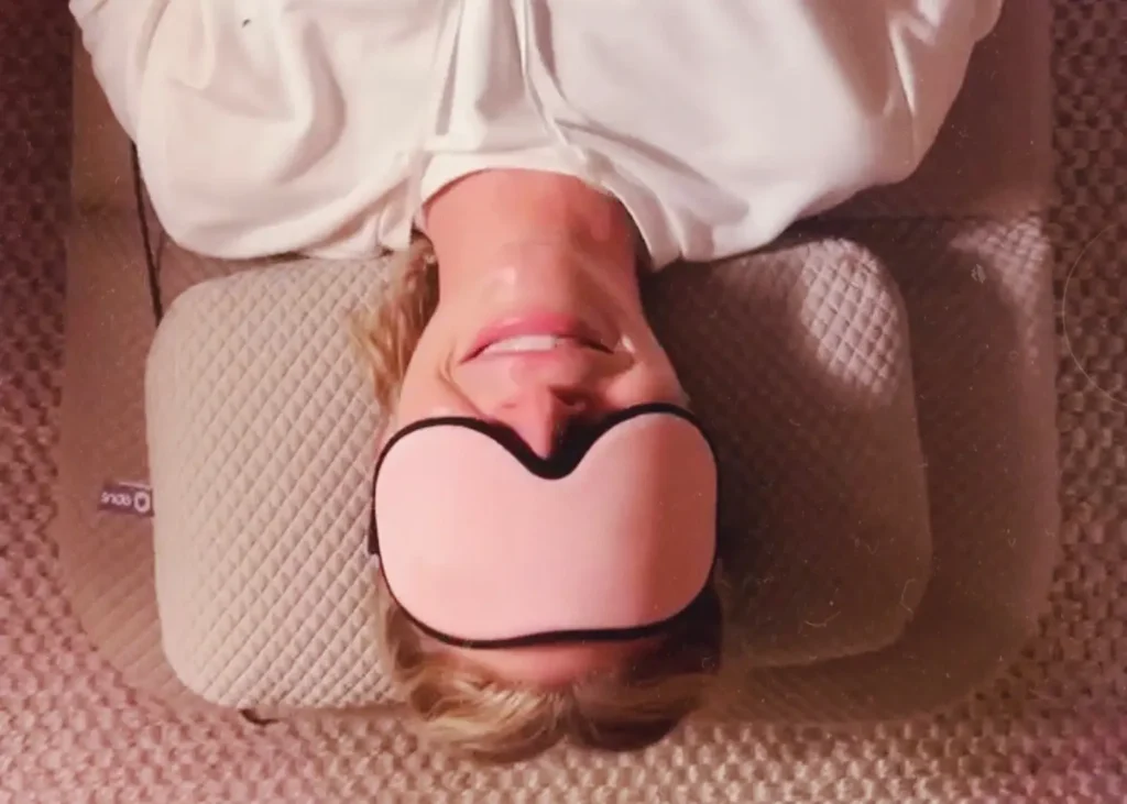 Soundbed therapy for stress relief with a smiling woman lying comfortably with an eye mask.