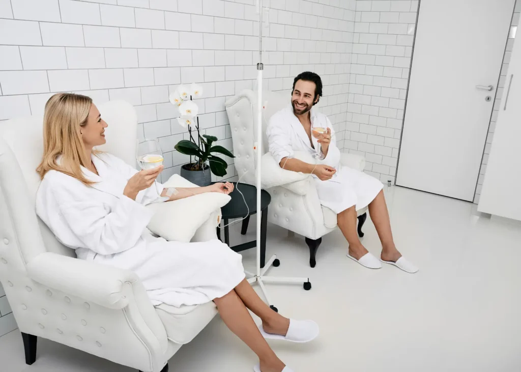 Ketamine infusion for depression with two people in robes receiving IV drips while sitting comfortably and drinking water.